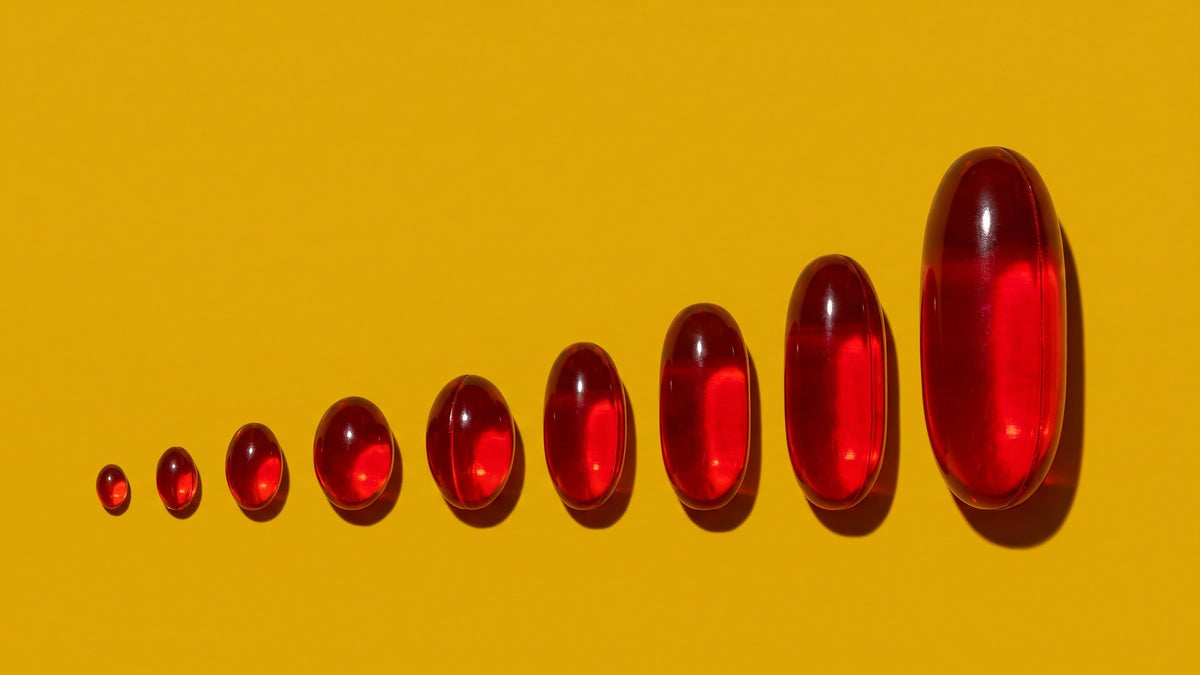 A row of cranberry softgels rising from tiny to enormous - the cranberry pill dose gap - ADIRA