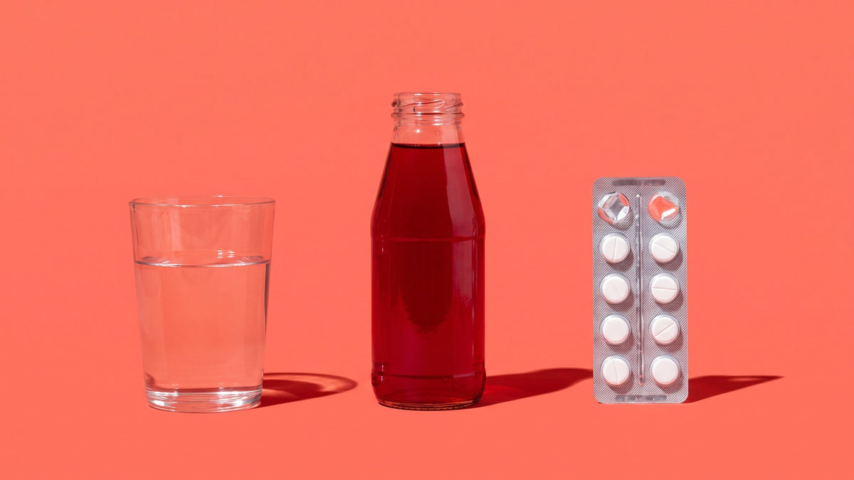 A glass of water, a bottle of cranberry juice and a blister of antibiotics lined up - the three answers usually given for UTI causes - ADIRA