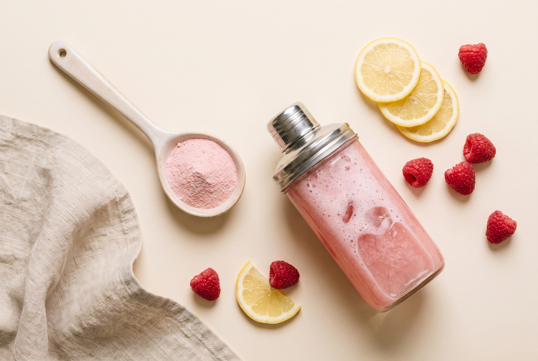 Pink creatine scoop, shaker and fruit flat lay